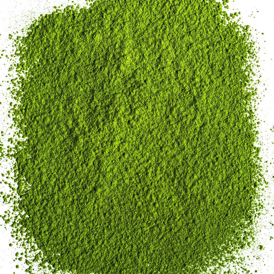 A mound of bright green matcha powder spilled on a clean white background.