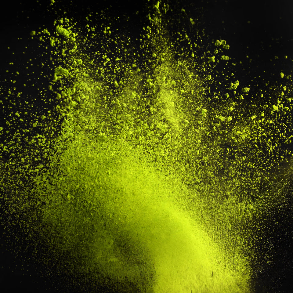 Vibrant lime green powder exploding in a dramatic spray against a solid black background.